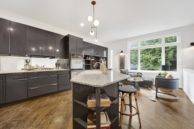 826 S Bell Ave, Chicago, IL 60612 - kitchen with white double oven, dark wood-type flooring, a breakfast bar, a kitchen island, and hanging light fixtures