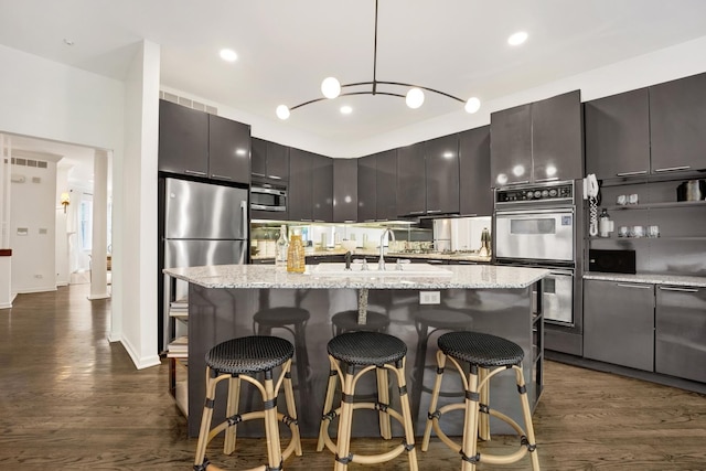 826 S Bell Ave, Chicago, IL 60612 - kitchen with stainless steel appliances, dark wood-style floors, a kitchen island with sink, light stone countertops, and recessed lighting