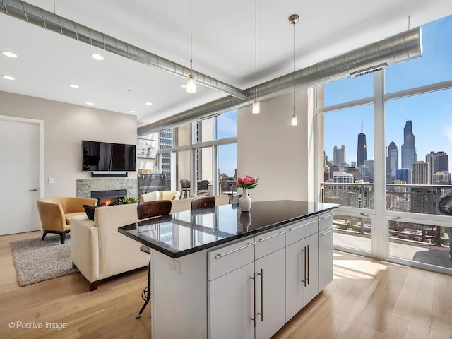 700 N Larrabee St Unit 2008, Chicago, IL 60654 - kitchen featuring a wall of windows, light wood finished floors, a warm lit fireplace, a center island, and a breakfast bar area