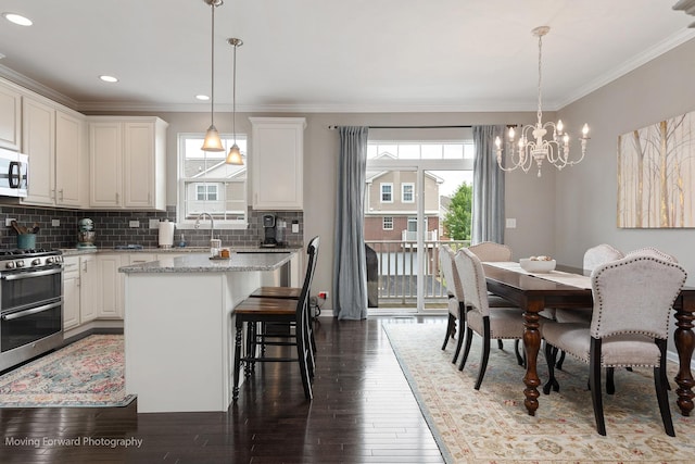 15383 Silver Bell Rd, Orland Park, IL 60462 - kitchen featuring appliances with stainless steel finishes, a kitchen island, dark wood-style flooring, a chandelier, and a breakfast bar