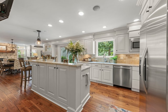 1563 Abbotsford Dr, Naperville, IL 60563 - kitchen with stainless steel appliances, a kitchen island, white cabinetry, dark wood-style flooring, and tasteful backsplash