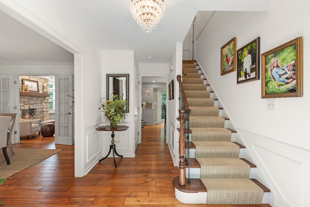 1563 Abbotsford Dr, Naperville, IL 60563 - stairs with a chandelier, hardwood / wood-style floors, a stone fireplace, and ornamental molding