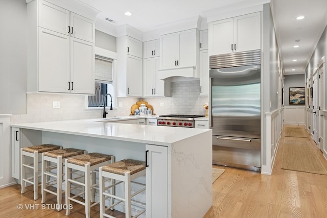 4321 N Paulina St Unit 2N, Chicago, IL 60613 - kitchen with stainless steel built in fridge, light wood-style flooring, a peninsula, light countertops, and recessed lighting