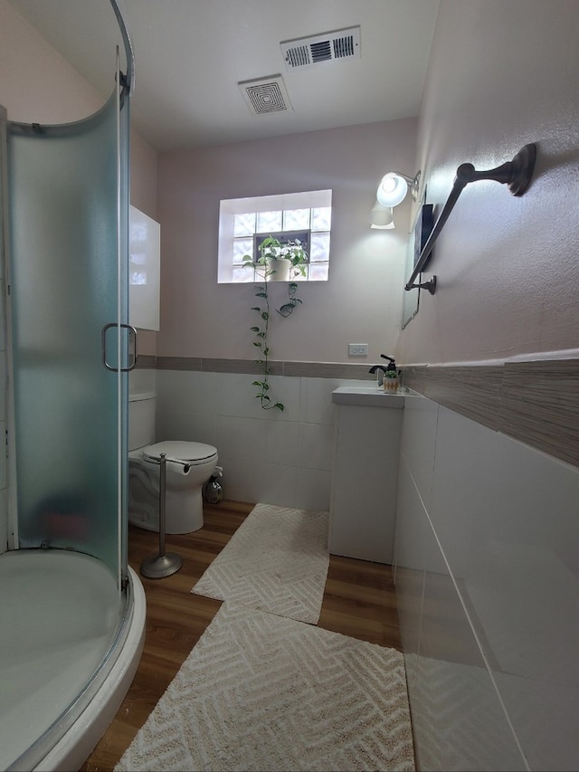 bathroom with vanity, a shower stall, wood finished floors, and tile walls