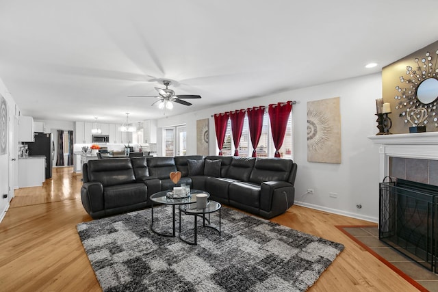 21222 Vivienne Dr, Matteson, IL 60443 - living area featuring a ceiling fan, a tiled fireplace, light wood-style flooring, a chandelier, and recessed lighting