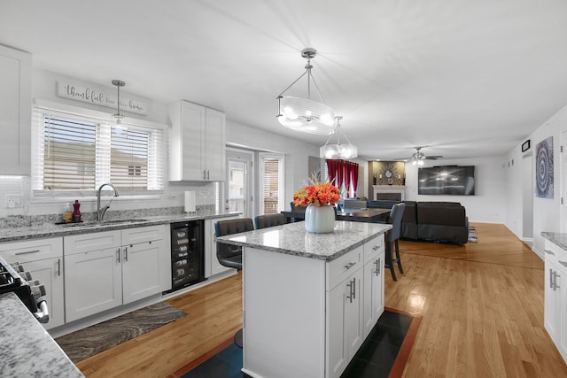 21222 Vivienne Dr, Matteson, IL 60443 - kitchen with wine cooler, white cabinetry, a center island, open floor plan, and a chandelier
