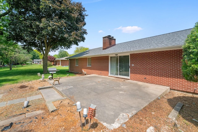 212 Forsythe Ln, Dekalb, IL 60115 - back of house with a yard, brick siding, a chimney, roof with shingles, and a patio