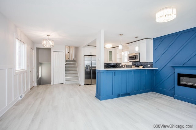 9154 S Luella Ave, Chicago, IL 60617 - kitchen with stainless steel appliances, a chandelier, a peninsula, white cabinets, and light wood-style flooring