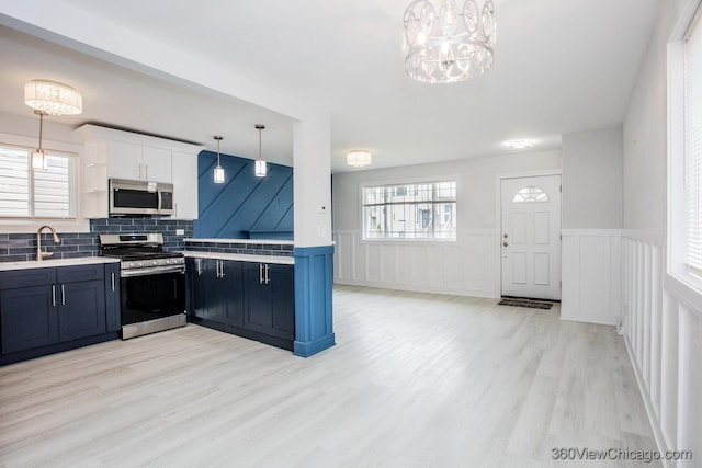 9154 S Luella Ave, Chicago, IL 60617 - kitchen with appliances with stainless steel finishes, light wood-type flooring, light countertops, a chandelier, and a wainscoted wall