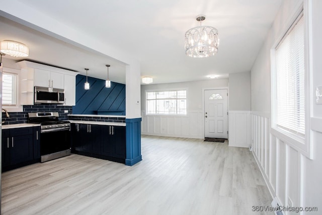 9154 S Luella Ave, Chicago, IL 60617 - kitchen featuring appliances with stainless steel finishes, dark cabinetry, light countertops, light wood-style floors, and a wainscoted wall