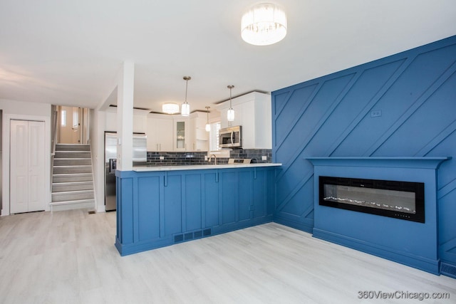 9154 S Luella Ave, Chicago, IL 60617 - kitchen featuring stainless steel appliances, a peninsula, glass insert cabinets, light wood-style floors, and white cabinets
