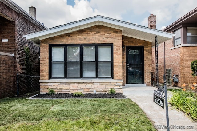 9206 S Yates Blvd, Chicago, IL 60617 - view of exterior entry featuring a yard, brick siding, and a chimney