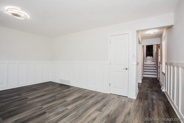 9206 S Yates Blvd, Chicago, IL 60617 - unfurnished room featuring wainscoting, dark wood-style flooring, and stairs