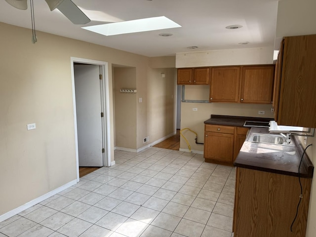 8114 S Anthony Ave, Chicago, IL 60617 - kitchen with dark countertops, brown cabinetry, a skylight, and light tile patterned flooring