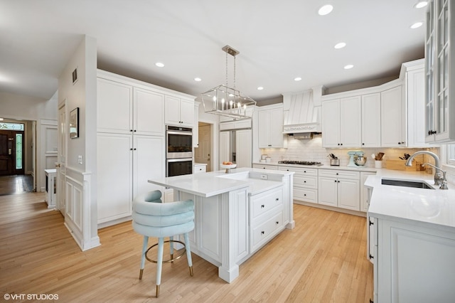2007 Wilmette Ave, Wilmette, IL 60091 - kitchen with stainless steel double oven, a center island, light wood finished floors, white cabinetry, and tasteful backsplash