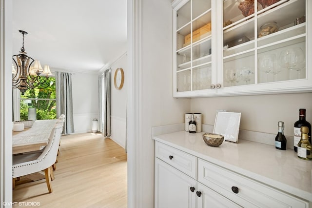 2007 Wilmette Ave, Wilmette, IL 60091 - bar featuring light wood-style floors, a chandelier, pendant lighting, ornamental molding, and a wainscoted wall