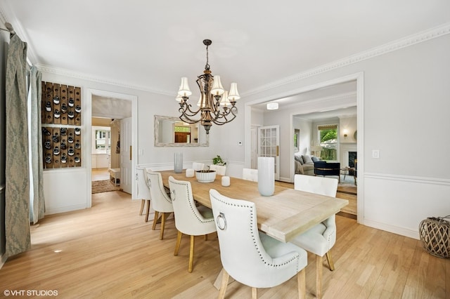 2007 Wilmette Ave, Wilmette, IL 60091 - dining area featuring a chandelier, light wood-type flooring, crown molding, a lit fireplace, and a wainscoted wall