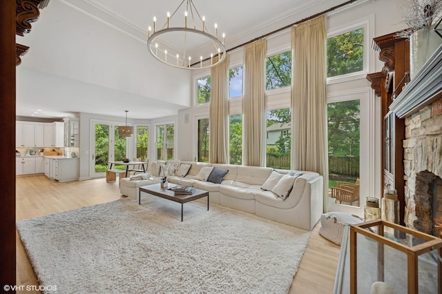 2007 Wilmette Ave, Wilmette, IL 60091 - living room with light wood-style flooring, a towering ceiling, a stone fireplace, a chandelier, and crown molding
