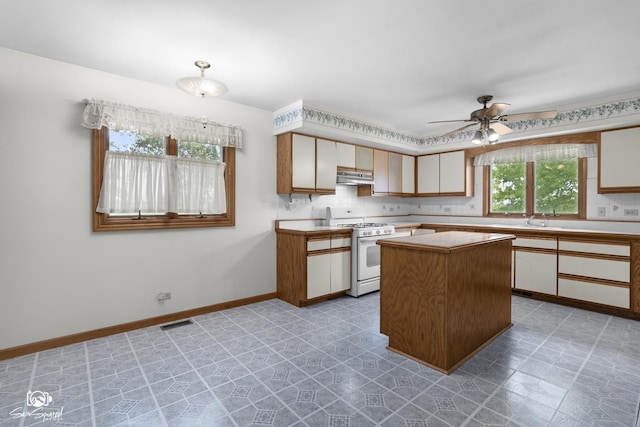 4849 W Kennedy Rd, Peotone, IL 60468 - kitchen with white range with gas cooktop, light countertops, ceiling fan, a kitchen island, and under cabinet range hood