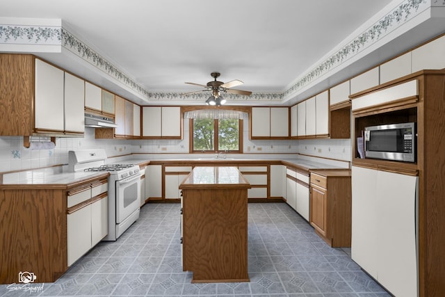 4849 W Kennedy Rd, Peotone, IL 60468 - kitchen featuring white range with gas stovetop, a ceiling fan, a kitchen island, stainless steel microwave, and backsplash