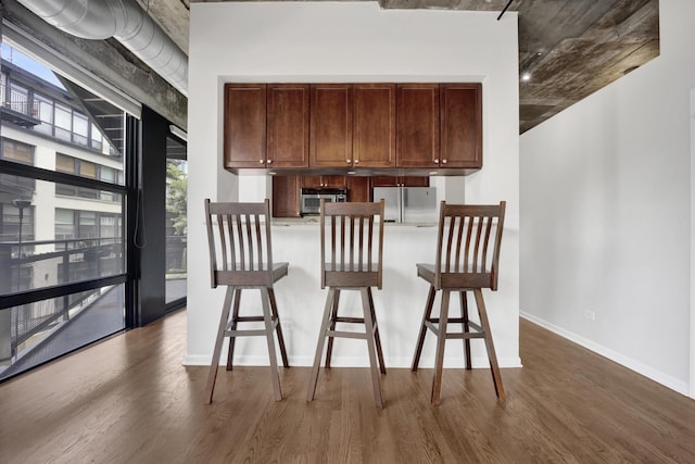 1070 W 15th St Unit 201, Chicago, IL 60608 - kitchen with freestanding refrigerator, a breakfast bar area, and dark wood-type flooring