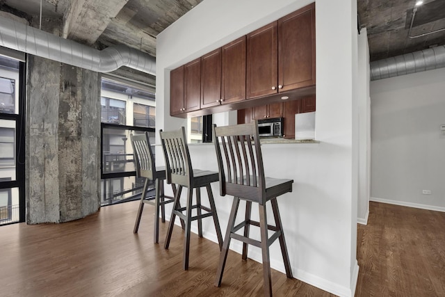 1070 W 15th St Unit 201, Chicago, IL 60608 - kitchen featuring dark wood-style flooring, stainless steel microwave, a breakfast bar area, refrigerator, and light countertops