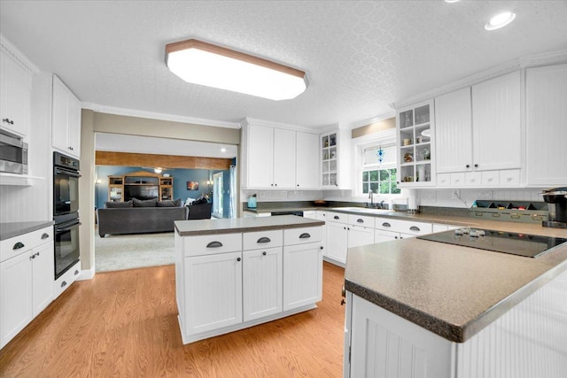 19615 116th Ave, Mokena, IL 60448 - kitchen featuring black appliances, dark countertops, light wood finished floors, glass insert cabinets, and white cabinetry