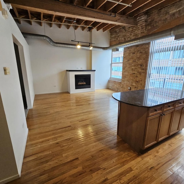 420 S Clinton St Unit 607-A, Chicago, IL 60607 - unfurnished living room with light wood-type flooring, a fireplace, brick wall, and rail lighting