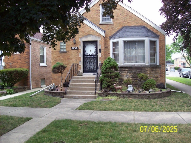 bungalow with brick siding and a front yard