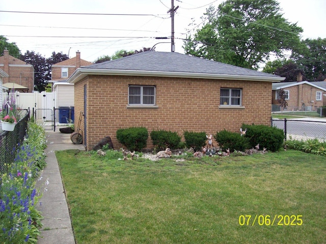 view of side of home featuring a gate, brick siding, and a shingled roof