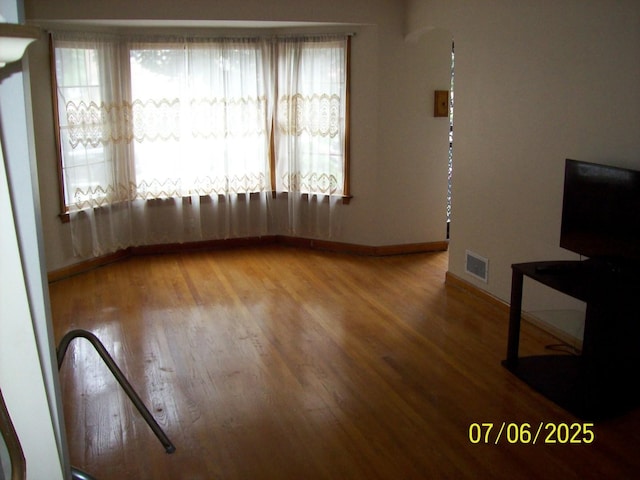 unfurnished living room featuring wood finished floors and baseboards