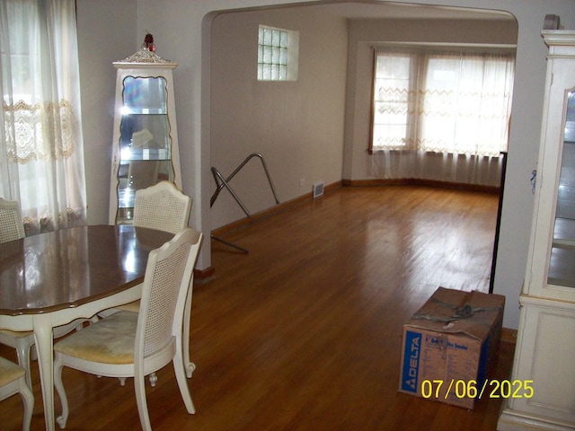 unfurnished dining area with wood finished floors and arched walkways