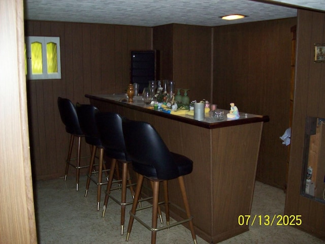 indoor dry bar with wood walls and tile patterned floors