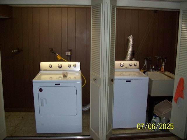 washroom featuring washer and clothes dryer and wood walls