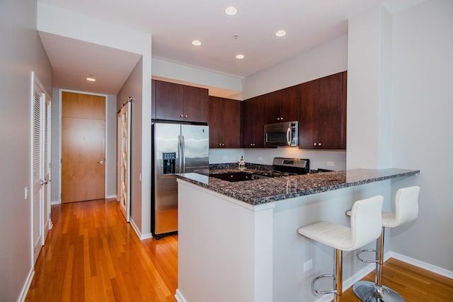 500 W Superior St Unit 1004, Chicago, IL 60654 - kitchen with stainless steel appliances, light wood-type flooring, a breakfast bar area, dark stone countertops, and a peninsula