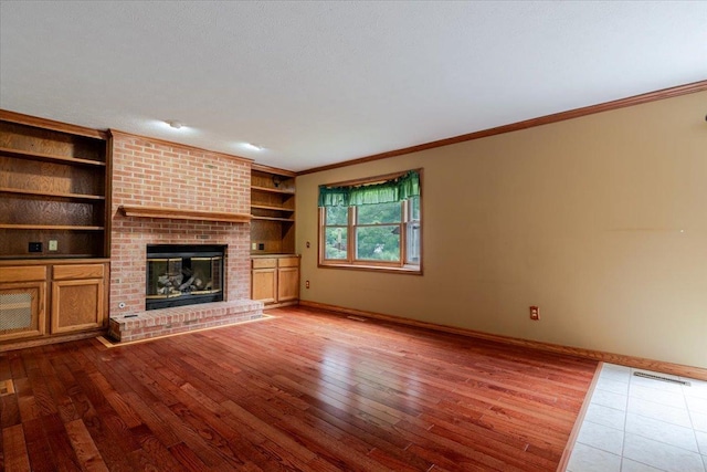 201 N Broadway St, Hudson, IL 61748 - unfurnished living room with crown molding, wood finished floors, a fireplace, and built in features