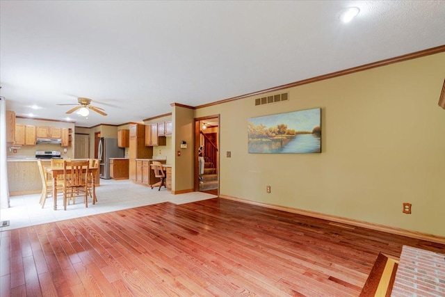 201 N Broadway St, Hudson, IL 61748 - unfurnished living room featuring light wood-style flooring, ornamental molding, ceiling fan, and stairway