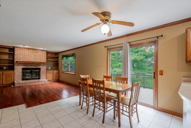 201 N Broadway St, Hudson, IL 61748 - dining area with a ceiling fan, light tile patterned flooring, ornamental molding, built in shelves, and a brick fireplace