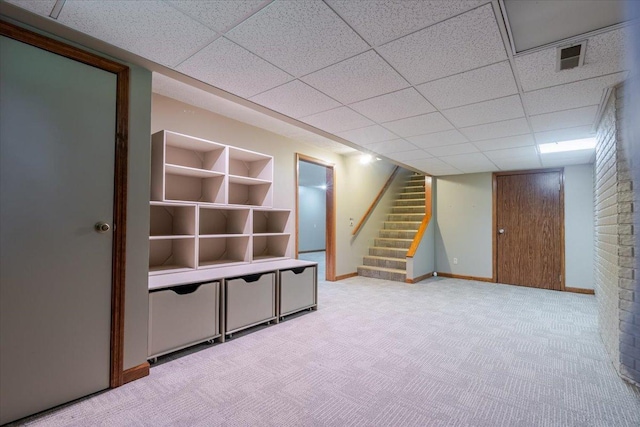 201 N Broadway St, Hudson, IL 61748 - finished below grade area with light carpet, stairway, and a paneled ceiling