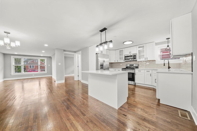 819 E 98th Pl, Chicago, IL 60628 - kitchen featuring open floor plan, appliances with stainless steel finishes, decorative backsplash, a kitchen island, and glass insert cabinets