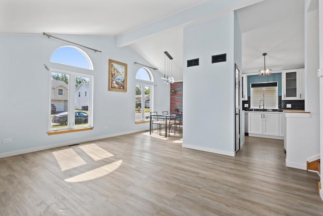 22514 Plum Creek Dr, Sauk Village, IL 60411 - unfurnished living room featuring a chandelier, light wood-type flooring, beam ceiling, and high vaulted ceiling