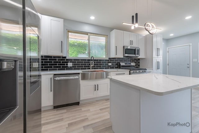 9340 S Elizabeth St, Chicago, IL 60620 - kitchen with stainless steel appliances, decorative backsplash, white cabinets, light wood-style floors, and hanging light fixtures
