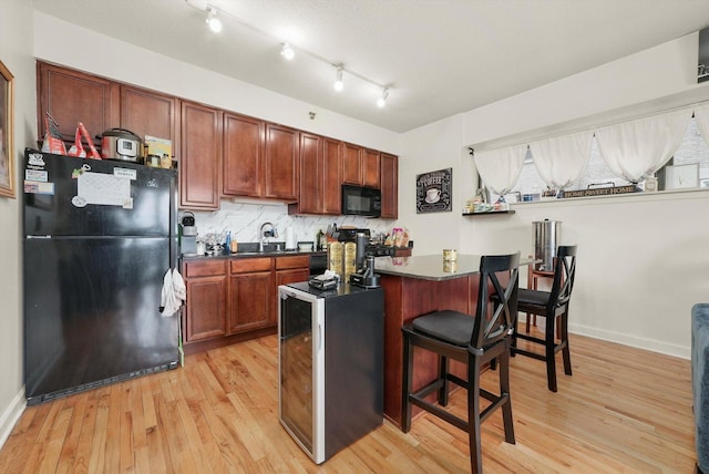41 E 8th St Unit 1404, Chicago, IL 60605 - kitchen featuring black appliances, dark countertops, light wood finished floors, a breakfast bar area, and backsplash
