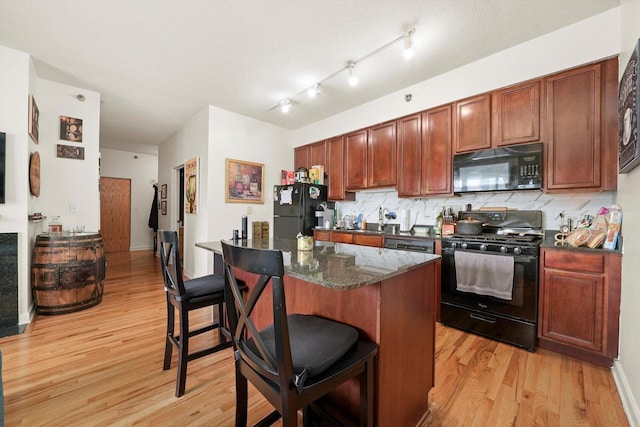 41 E 8th St Unit 1404, Chicago, IL 60605 - kitchen featuring black appliances, light wood-style flooring, a kitchen breakfast bar, tasteful backsplash, and a center island