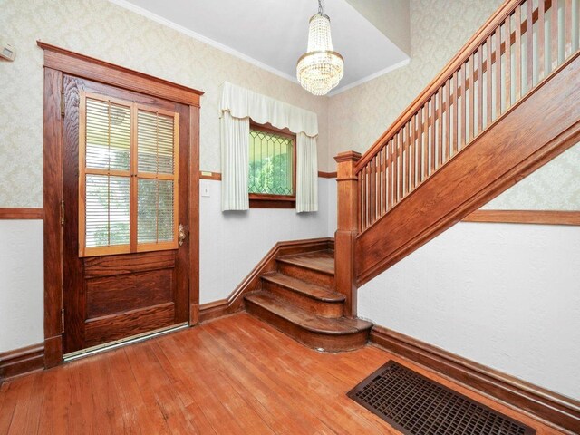31 Bluff Ave, La Grange, IL 60525 - foyer entrance with wood-type flooring, a chandelier, stairway, wallpapered walls, and ornamental molding