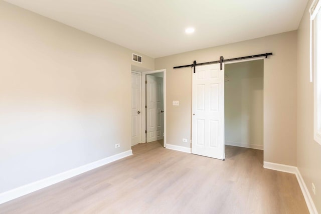 129 Highbury Dr, Elgin, IL 60120 - unfurnished bedroom with light wood-style flooring, a barn door, and recessed lighting