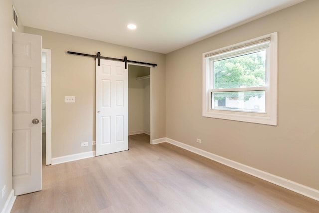 129 Highbury Dr, Elgin, IL 60120 - unfurnished bedroom featuring a barn door, light wood-type flooring, recessed lighting, and a closet