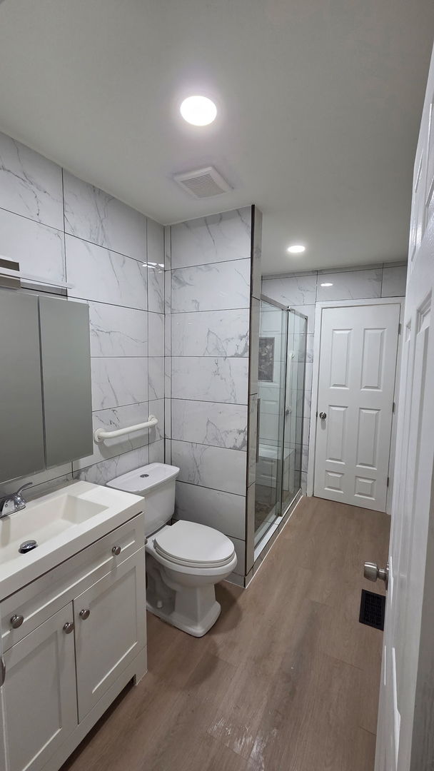 129 Highbury Dr, Elgin, IL 60120 - bathroom with tile walls, wood finished floors, vanity, and a stall shower