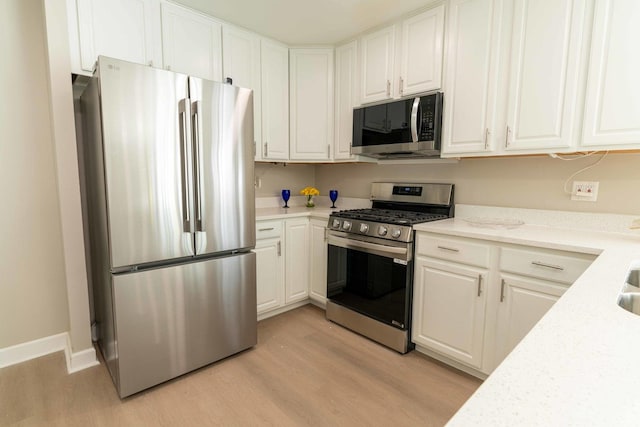 129 Highbury Dr, Elgin, IL 60120 - kitchen featuring appliances with stainless steel finishes, light wood-type flooring, white cabinetry, and light stone countertops