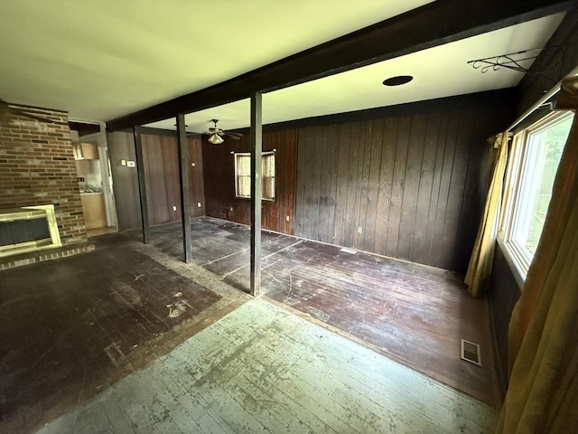 24576 W Norelius Ave, Round Lake, IL 60073 - unfurnished living room with healthy amount of natural light, a brick fireplace, wood walls, and a ceiling fan